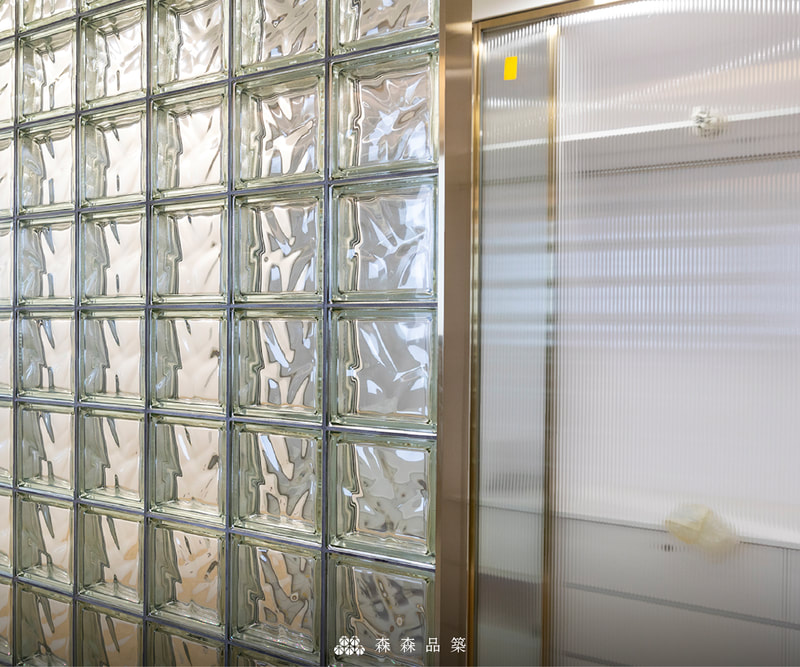 森森品築Q19 玻璃空心磚住宅浴室隔間設計案例分享 - 主臥室浴室隔間牆上，玻璃磚以理性排列方式呈現，與金色鐵件搭配相呼應。Q19OMET金屬塗層磚和2mm固定架，達細緻縫寬效果。